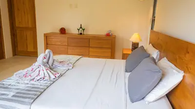a bedroom with a white bed with a wooden headboard at House 15 min from the beach with river access in Ojochal