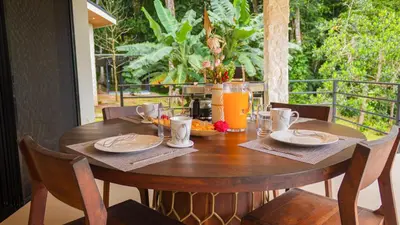 a wooden table with food and orange juice on a porch at House 15 min from the beach with river access in Ojochal