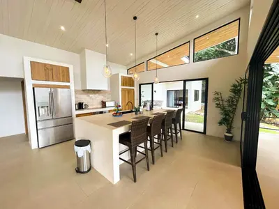 an open kitchen with a large island with bar chairs at House 15 min from the beach with river access in Ojochal