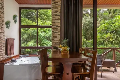 a dining room with a tub and a table and chairs at Cabañas Refugio Verde Monteverde in Monteverde Costa Rica