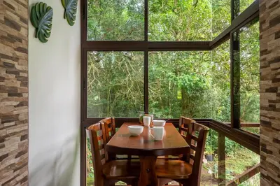 a table and chairs in a room with a large window at Cabañas Refugio Verde Monteverde in Monteverde Costa Rica