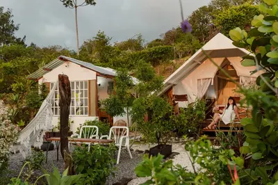 a woman sitting in front of a house at Monteverde Alas Glamping in Monteverde Costa Rica