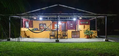 a small yellow house with chairs and lights at Hacienda el Paraíso in Guápiles