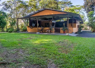 a building with a grassy yard in front of it at Hacienda el Paraíso in Guápiles