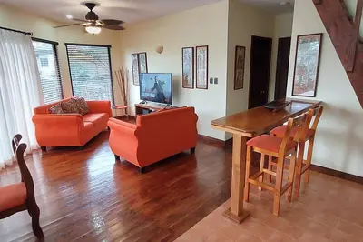 a living room with orange chairs and a wooden table at Beautiful 3BR Lakeshore House in Gated Community in Tilarán