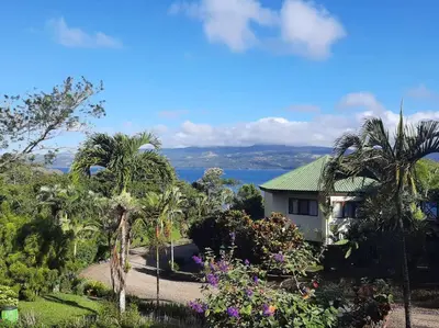 a house with palm trees and flowers in front of it at Beautiful 3BR Lakeshore House in Gated Community in Tilarán