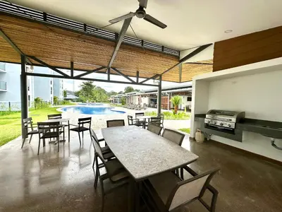 a dining room with a table and chairs and a pool at Viva in Jacó