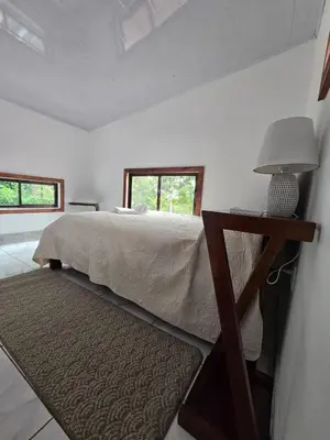 a bedroom with a bed and a table with a lamp at Happy Paradise Lodge in Nuevo Arenal