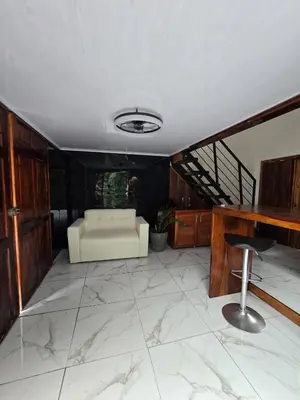 a living room with a white couch and a stool at Happy Paradise Lodge in Nuevo Arenal