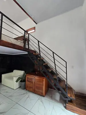 a spiral staircase in a living room with a couch at Happy Paradise Lodge in Nuevo Arenal