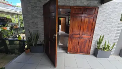 an open wooden door on a patio with plants at Happy Paradise Lodge in Nuevo Arenal