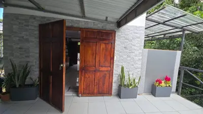 an open wooden door on a patio with potted plants at Happy Paradise Lodge in Nuevo Arenal
