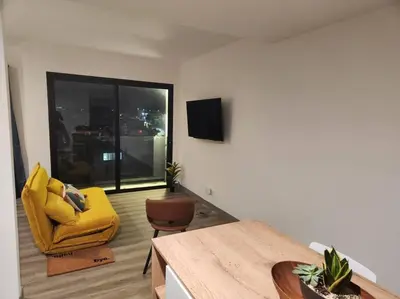 a living room with a yellow chair and a tv at Mountain View Estudio in Cinco Esquinas