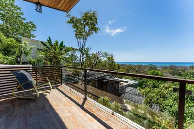 a deck with a chair sitting on top of it at Ocean Apartments- Walk to the beach in Santa Teresa Beach