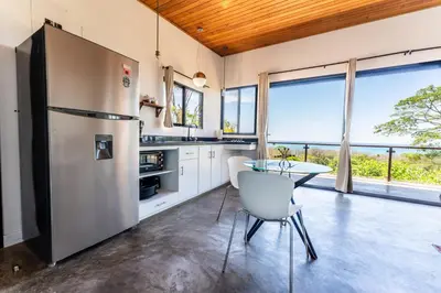a kitchen with a stainless steel refrigerator and a table at Ocean Apartments- Walk to the beach in Santa Teresa Beach