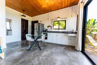 a kitchen with white cabinets and a table and chairs at Ocean Apartments- Walk to the beach in Santa Teresa Beach