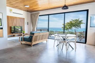 a living room with a table and chairs and a view of the ocean at Ocean Apartments- Walk to the beach in Santa Teresa Beach