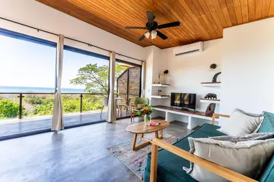 a living room with a couch and a table with a tv at Ocean Apartments- Walk to the beach in Santa Teresa Beach