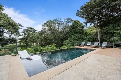 a swimming pool with two white chairs and trees at Stunning Villa with 3 Bedrooms Pool in Coco
