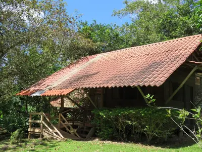 a house with a rusty roof on the grass at Vocaré Finca Agroecológica in Upala