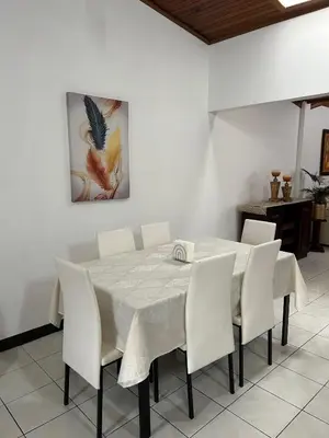 a dining room table with white chairs and a painting at SJO airport 4 min free parking in Alajuela City