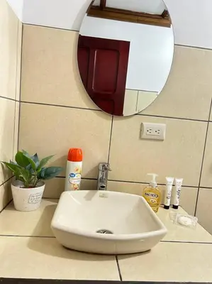 a white sink in a bathroom with a mirror at SJO airport 4 min free parking in Alajuela City