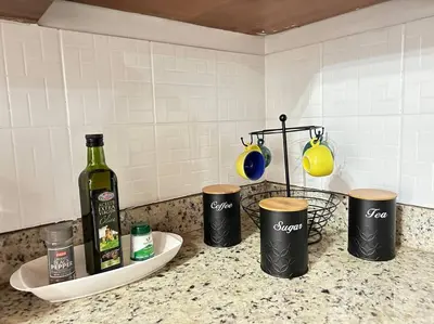a kitchen counter with a bottle of wine and three cups at SJO airport 4 min free parking in Alajuela City