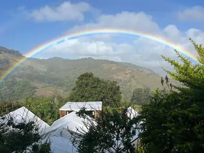 a rainbow over a house with mountains in the background at Alas House, Monteverde with amazing sunset view! in Monteverde Costa Rica