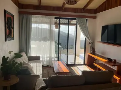 a living room with a couch and a table and a tv at Alas House, Monteverde with amazing sunset view! in Monteverde Costa Rica