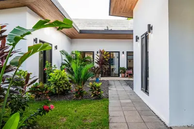 a courtyard of a house with plants and a pathway at Villa Serenity 4 bedroom 1 min walk to the beach in Santa Cruz