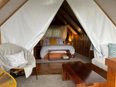 a bedroom with a bed and a couch in a tent at Alas Romantic Chalet Monteverde in Monteverde Costa Rica