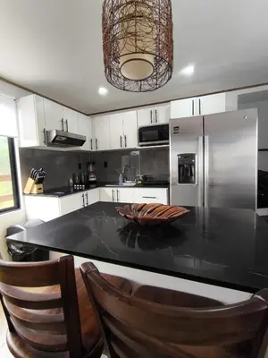 a kitchen with a black counter top and stainless steel appliances at Ventana Paraíso Cabaña con Jacuzzi in Alajuela City
