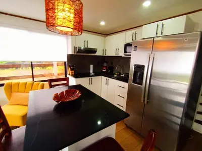a kitchen with a black counter and a refrigerator at Ventana Paraíso Cabaña con Jacuzzi in Alajuela City