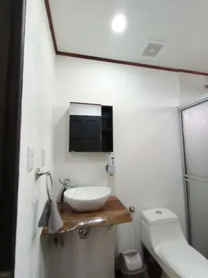 a bathroom with a sink and a toilet and a mirror at Ventana Paraíso Cabaña con Jacuzzi in Alajuela City