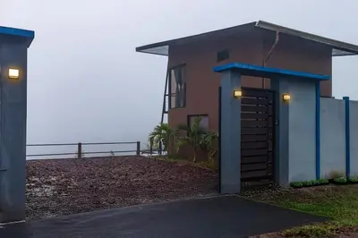 a small house with a gate in front of the ocean at Ventana Paraíso Cabaña con Jacuzzi in Alajuela City
