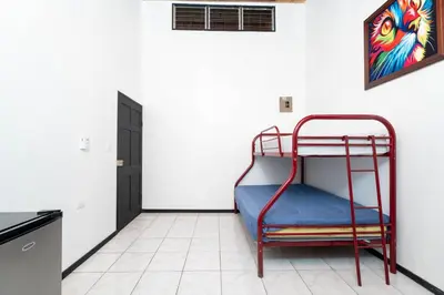 a red bunk bed in a white room with a door at Apartamento Frigia 3 in Quepos