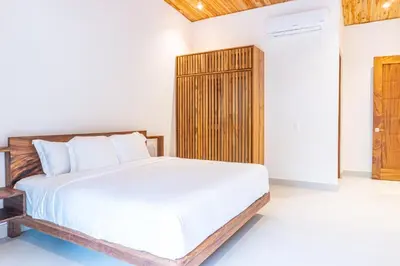 a bedroom with a white bed and a wooden cabinet at Coco Nosara Villas Guiones Family Resort Casa Rubi in Nicoya