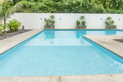 a swimming pool with blue water in front of a white wall at Coco Nosara Villas Guiones Family Resort Casa Juan in Nicoya