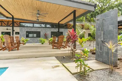 an outdoor patio with rocking chairs and a roof at Coco Nosara Villas Guiones Family Resort Casa Juan in Nicoya