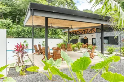 a pavilion with chairs and tables in a garden at Coco Nosara Villas Guiones Family Resort Casa Juan in Nicoya