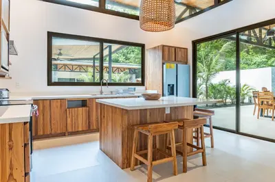 an open kitchen with wooden cabinets and a large island at Coco Nosara Villas Guiones Family Resort Casa Lluvia in Nicoya