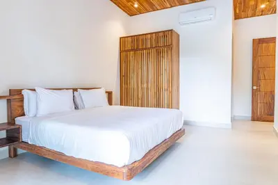 a bedroom with a white bed and a wooden cabinet at Coco Nosara Villas Guiones Family Resort Casa Lluvia in Nicoya
