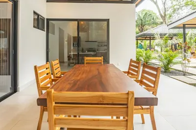 an open dining room with a wooden table and chairs at Coco Nosara Villas Guiones Family Resort Casa Lluvia in Nicoya
