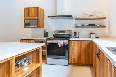 a kitchen with wooden cabinets and a stove top oven at Coco Nosara Villas Guiones Family Resort Casa Lluvia in Nicoya