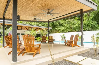 a wooden pergola with chairs and a table at Coco Nosara Villas Guiones Family Resort Casa Marie in Nicoya