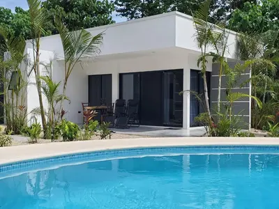 a house with a swimming pool in front of a house at one life villas avellanas walk to beach in Playa Avellana