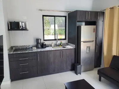 a kitchen with wooden cabinets and a refrigerator at one life villas avellanas walk to beach in Playa Avellana