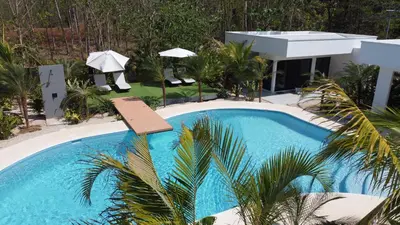 a swimming pool with a sign in front of a house at one life villas avellanas walk to beach in Playa Avellana