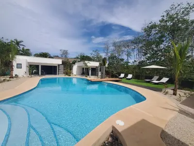 a large swimming pool with chairs and a house at one life villas avellanas walk to beach in Playa Avellana