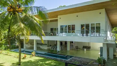 a large house with a balcony and a palm tree at Esterillos Lote home in Esterillos
